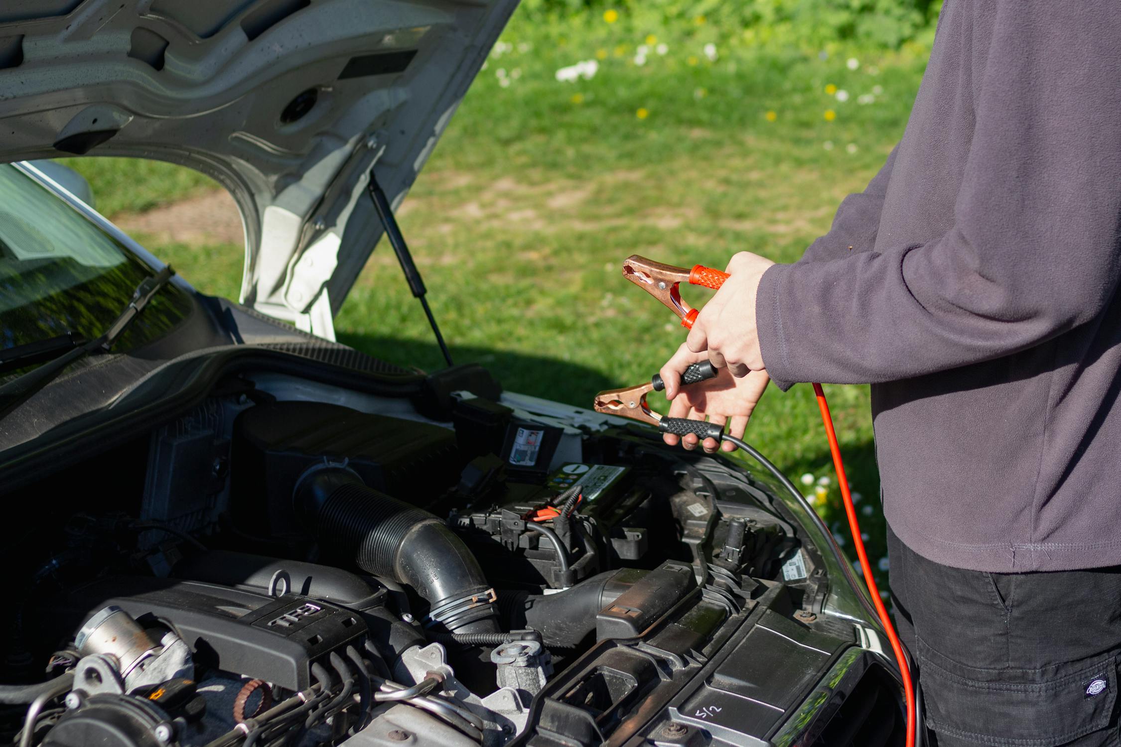Car battery service with jumper cables during electrical repair