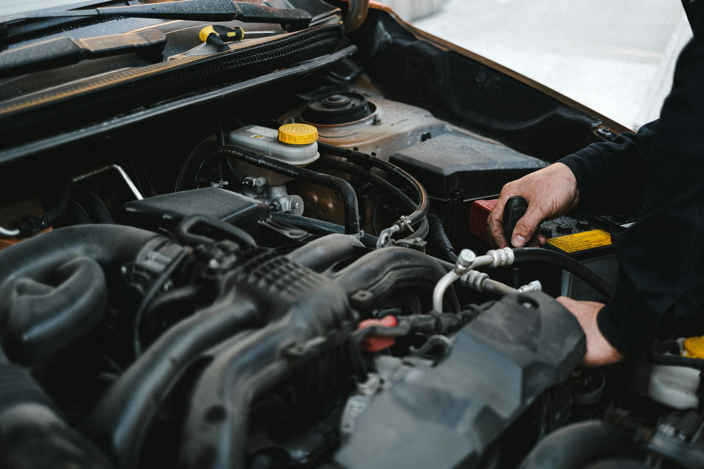 Mechanic hands deep in engine bay during engine repair service