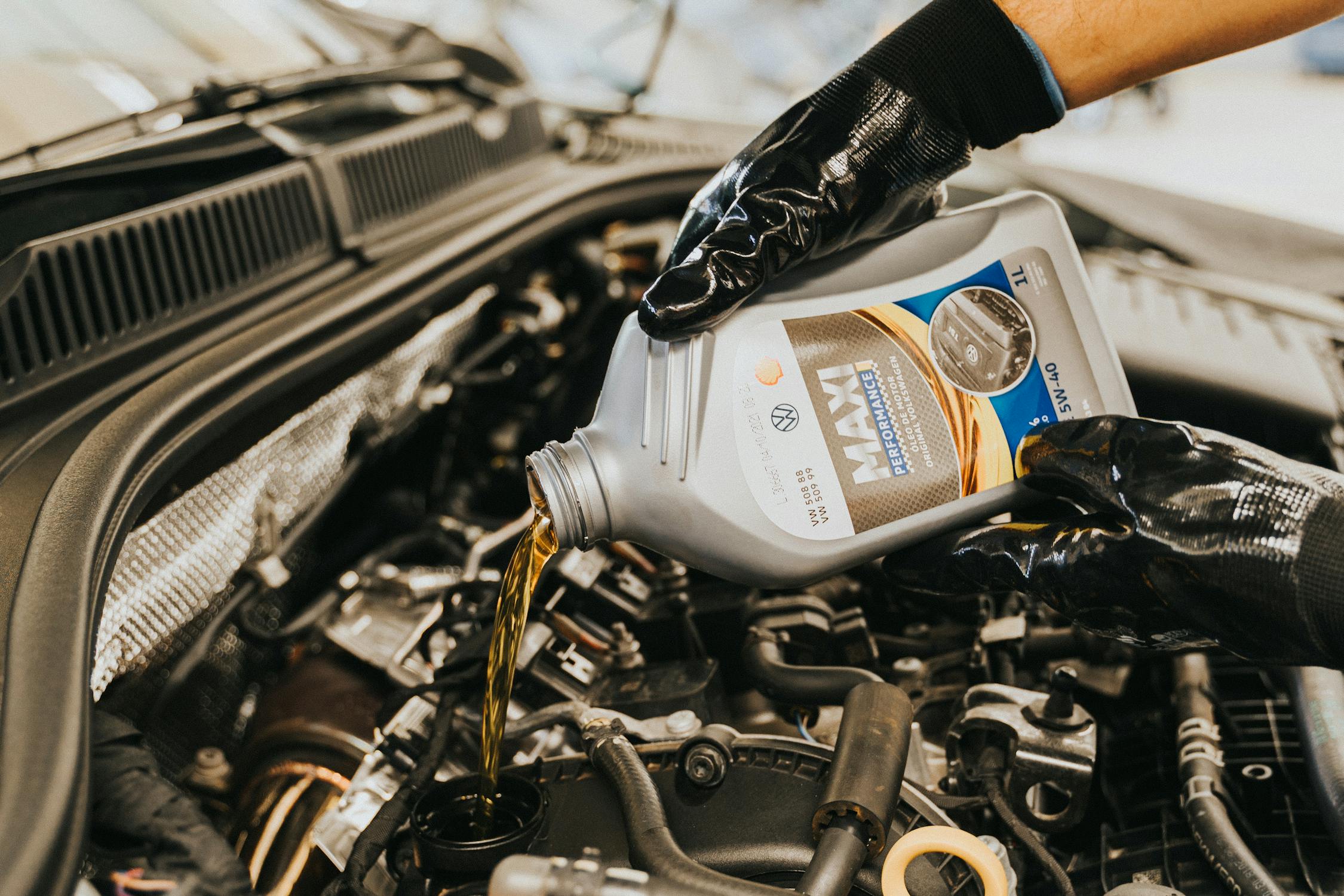Mechanic pouring synthetic motor oil into engine during oil change service