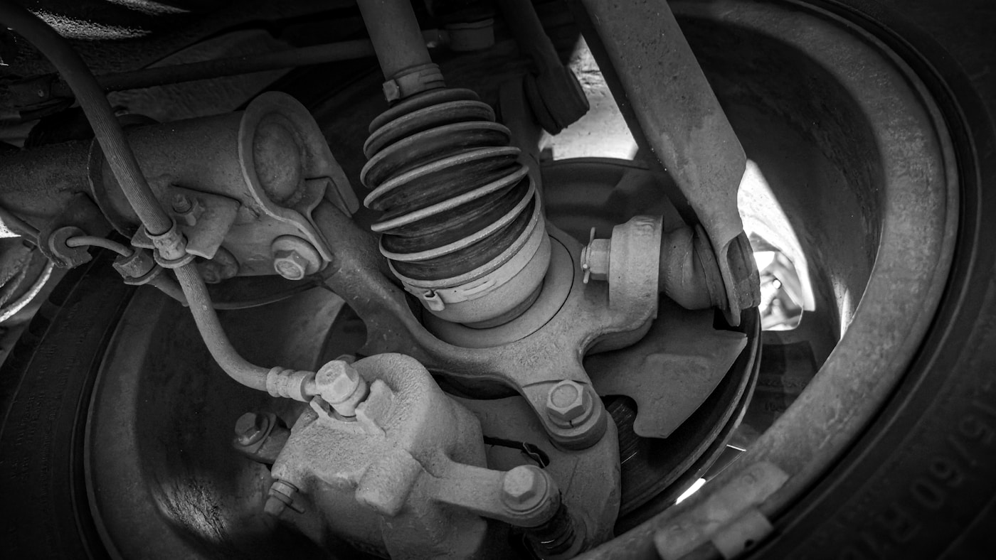 Mechanic performing wheel alignment and suspension check on lift